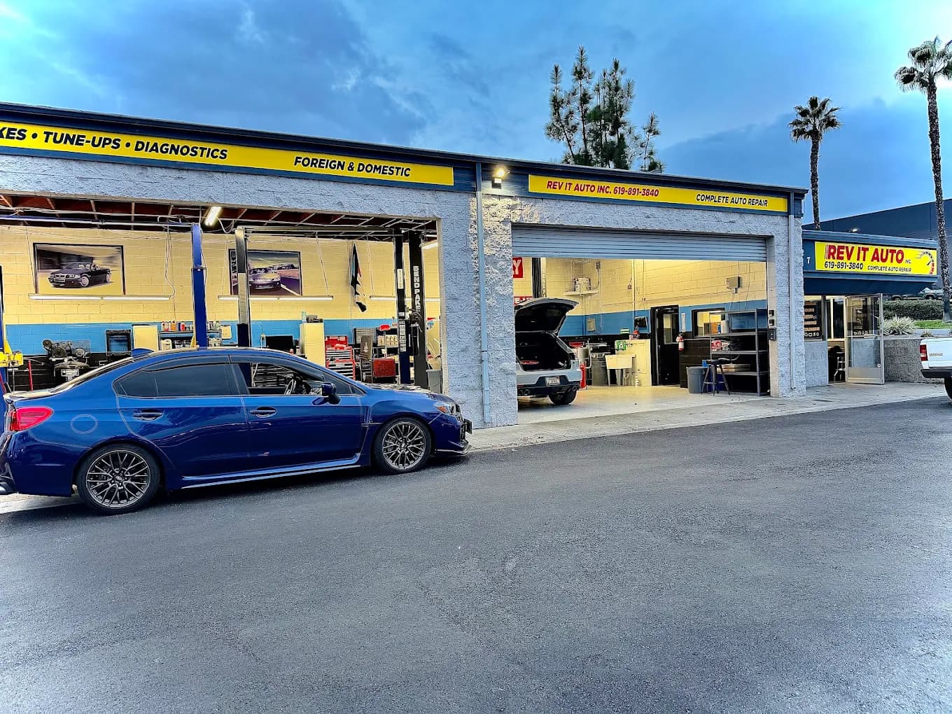 Rev It Auto Repair at dusk — Subaru WRX out front of the El Cajon shop